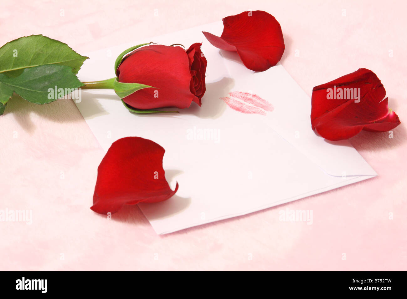 Still life of a red rose and petals on an envelope sealed with a kiss Stock Photo