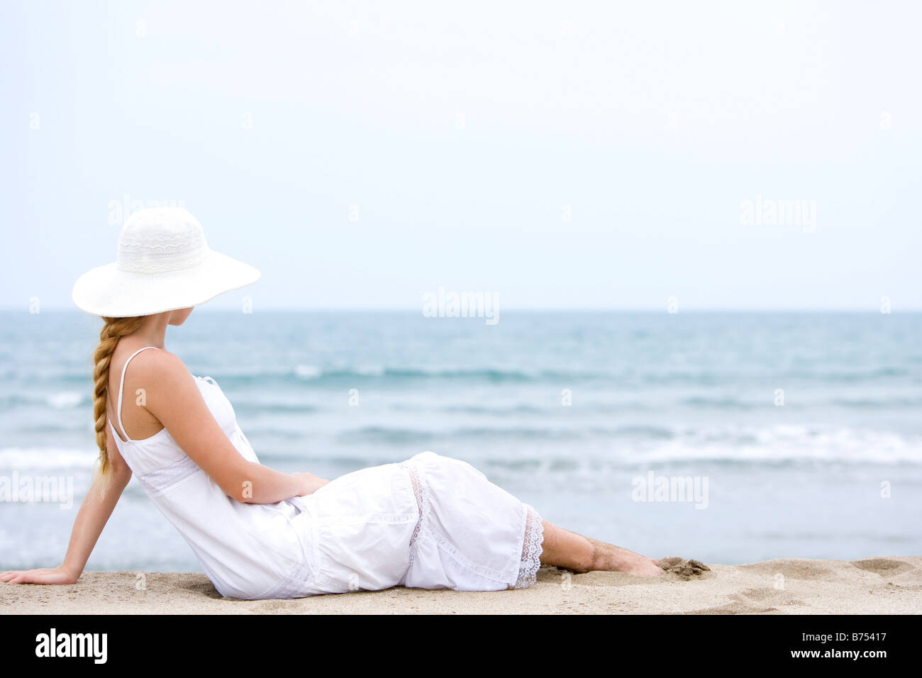 Young woman sitting on beach Stock Photo - Alamy