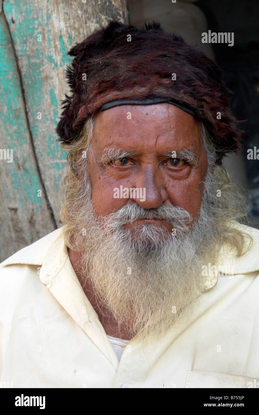 indian portrait of man with beard and traditional hat in the market in ...