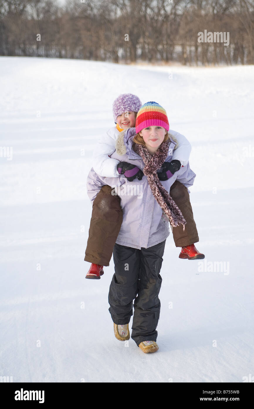 13 year old carries 9 year old up hill on back, Winnipeg, Canada Stock Photo