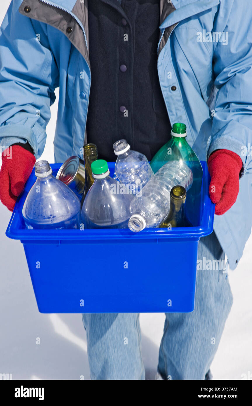 Homemaker taking out blue box full of bottles and cans for recycling Stock Photo