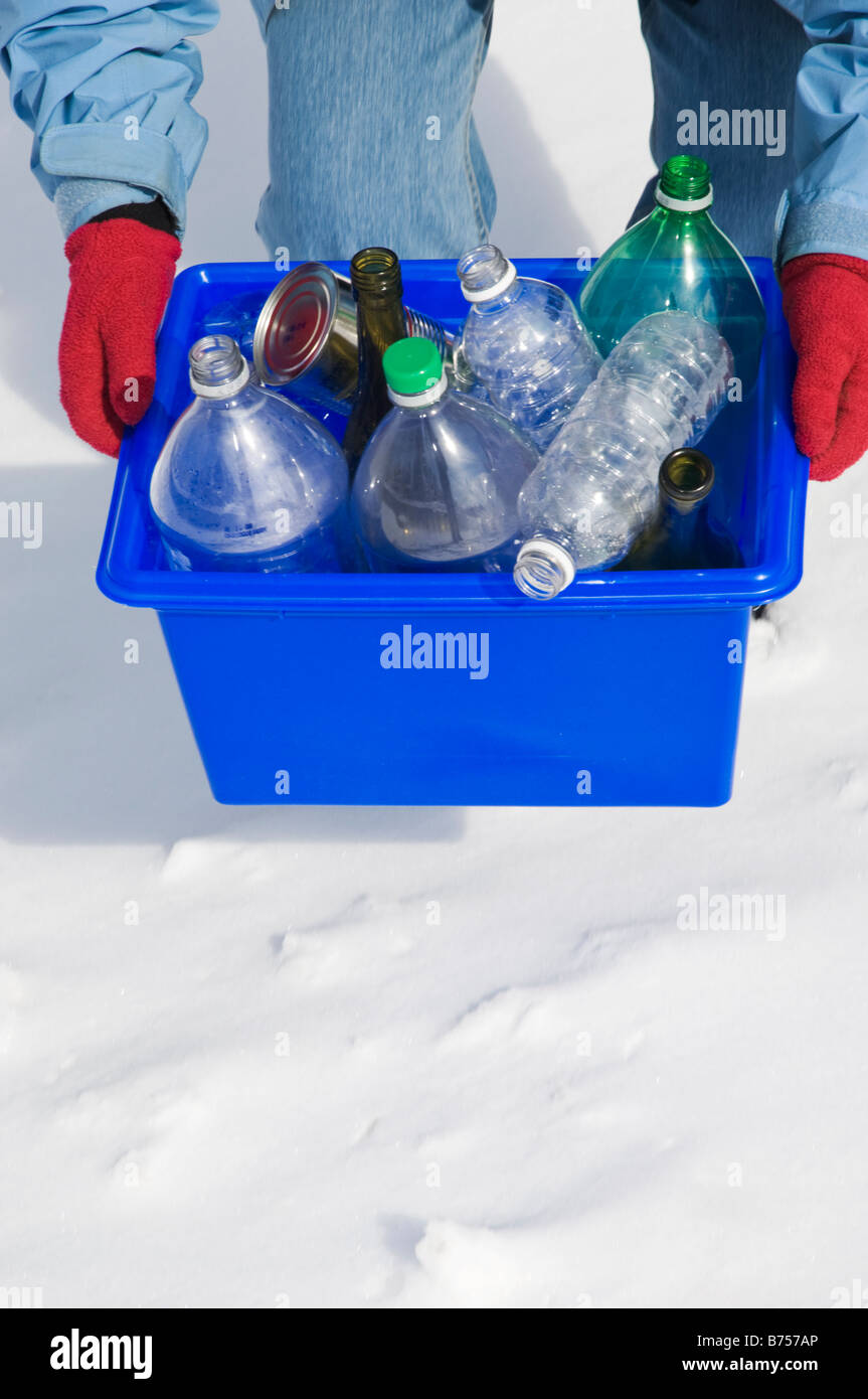 Homemaker taking out blue box full of bottles and cans for recycling Stock Photo