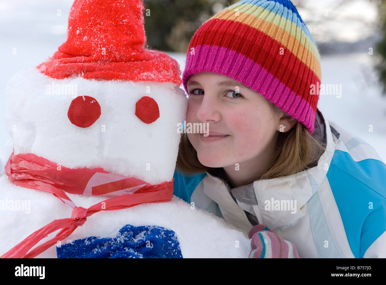 Thirteen year old girl beside snowman, Winnipeg, Canada Stock Photo