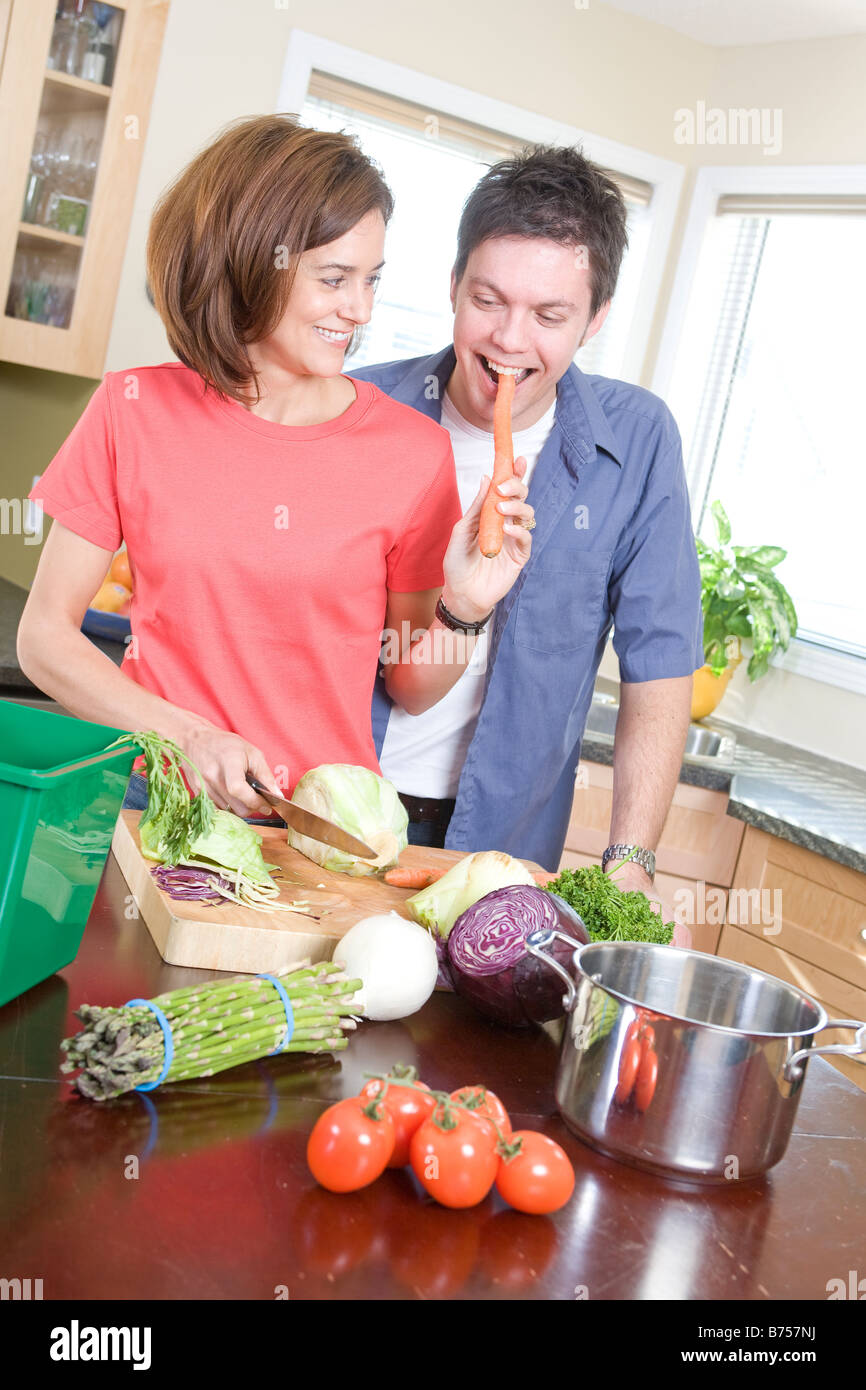 Couple in kitchen cutting vegetables beside kitchen compost bin, Winnipeg, Canada Stock Photo