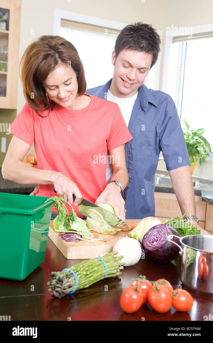 Couple in kitchen cutting vegetables beside kitchen compost bin, Winnipeg, Canada Stock Photo