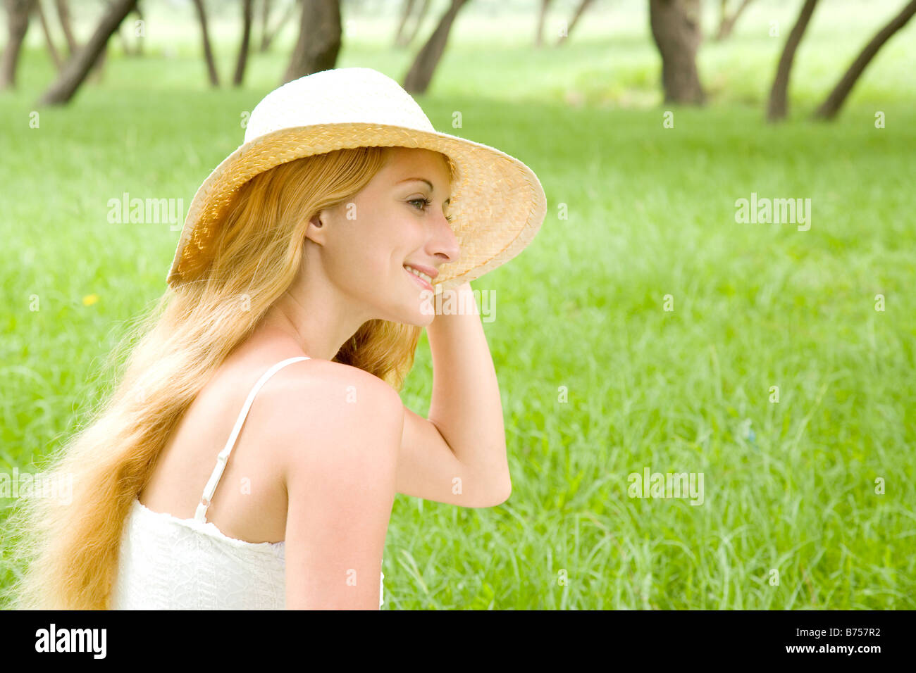Young woman wearing sun hat sitting on grass smiling portrait Stock ...