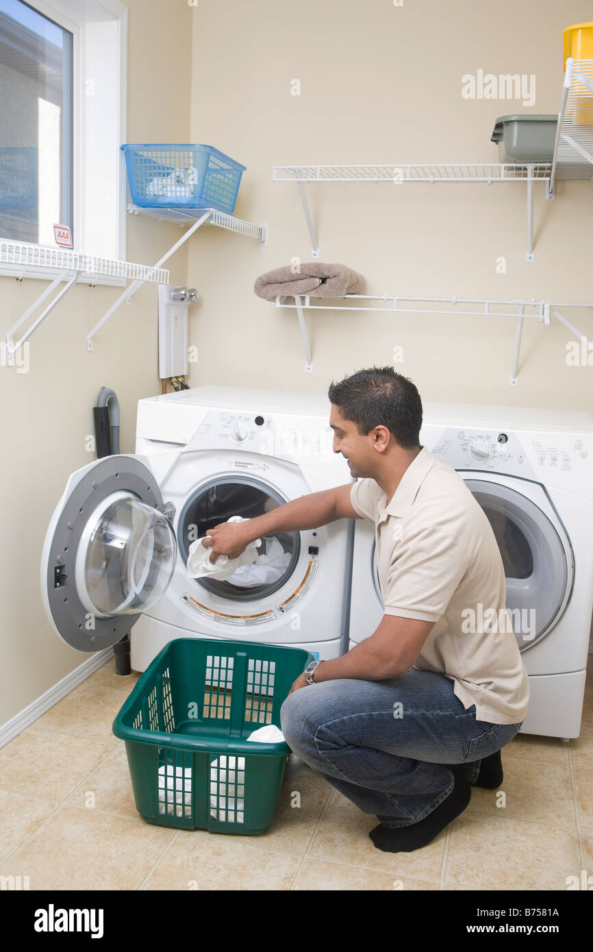 Man loading front loading washing machine with cloth diapers, Winnipeg, Canada Stock Photo