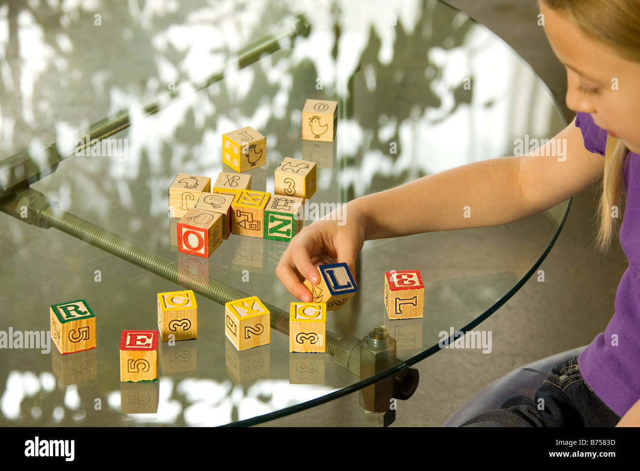 Young girl spelling recycle with alphabet blocks Stock Photo