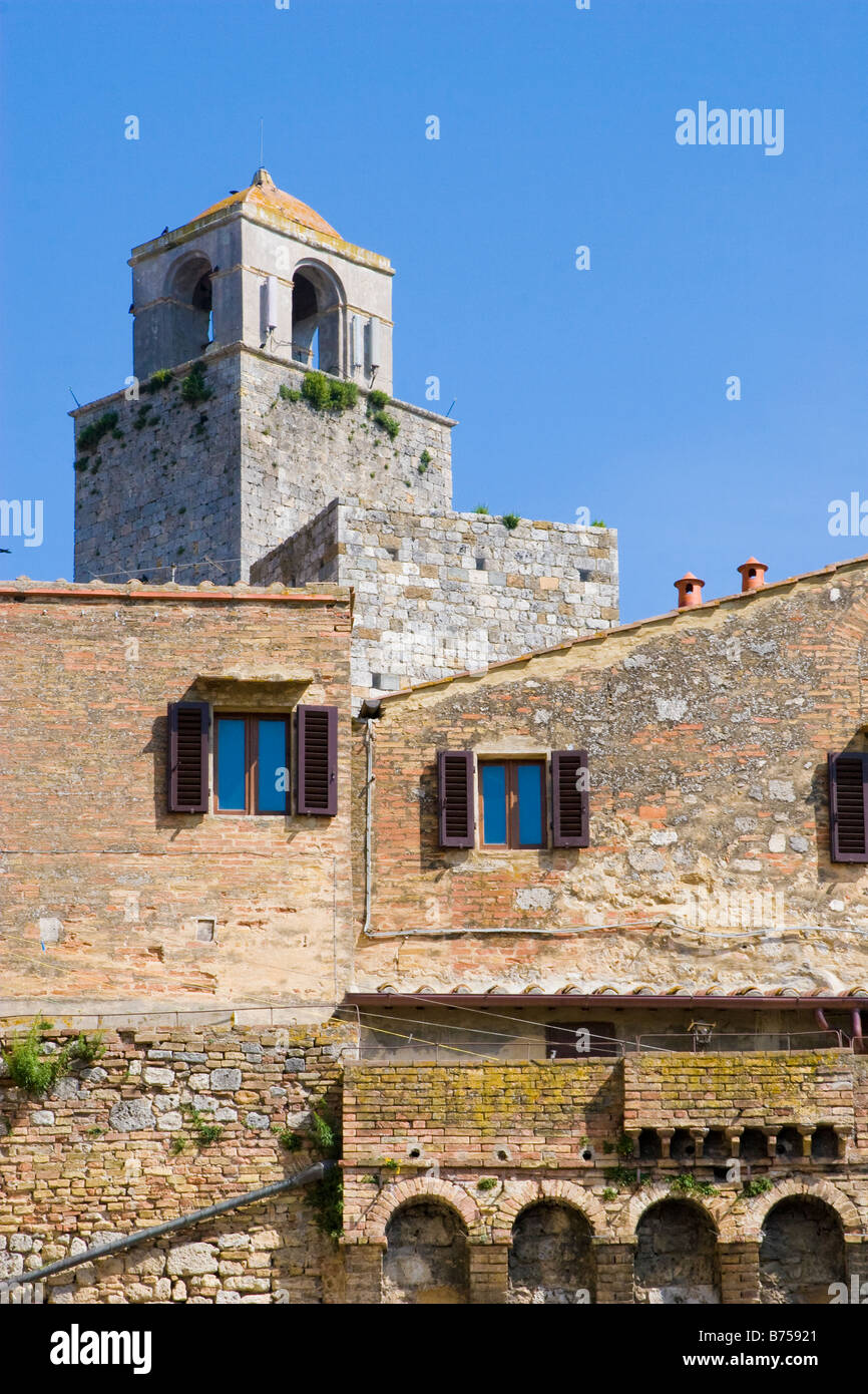 Bell tower emerging above ancient stone buildings in San Gimignano Italy Stock Photo