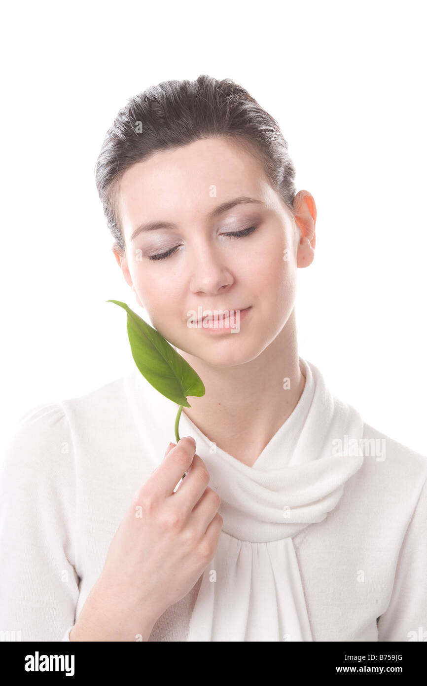 Young woman stroking her face with a leaf, Winnipeg, Manitoba Stock Photo