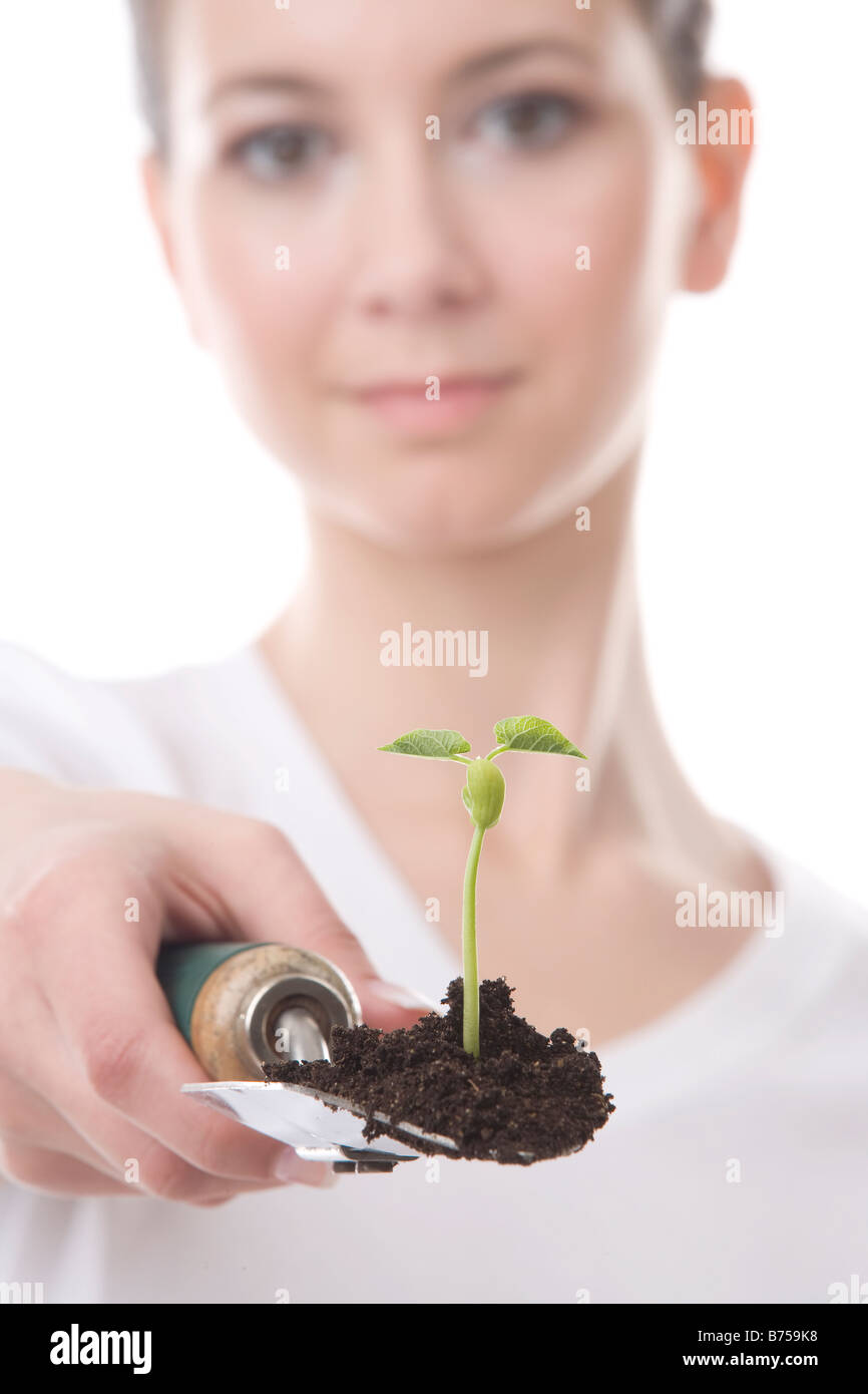 Face of a young woman with a trowel and small plant, Winnipeg, Manitoba Stock Photo