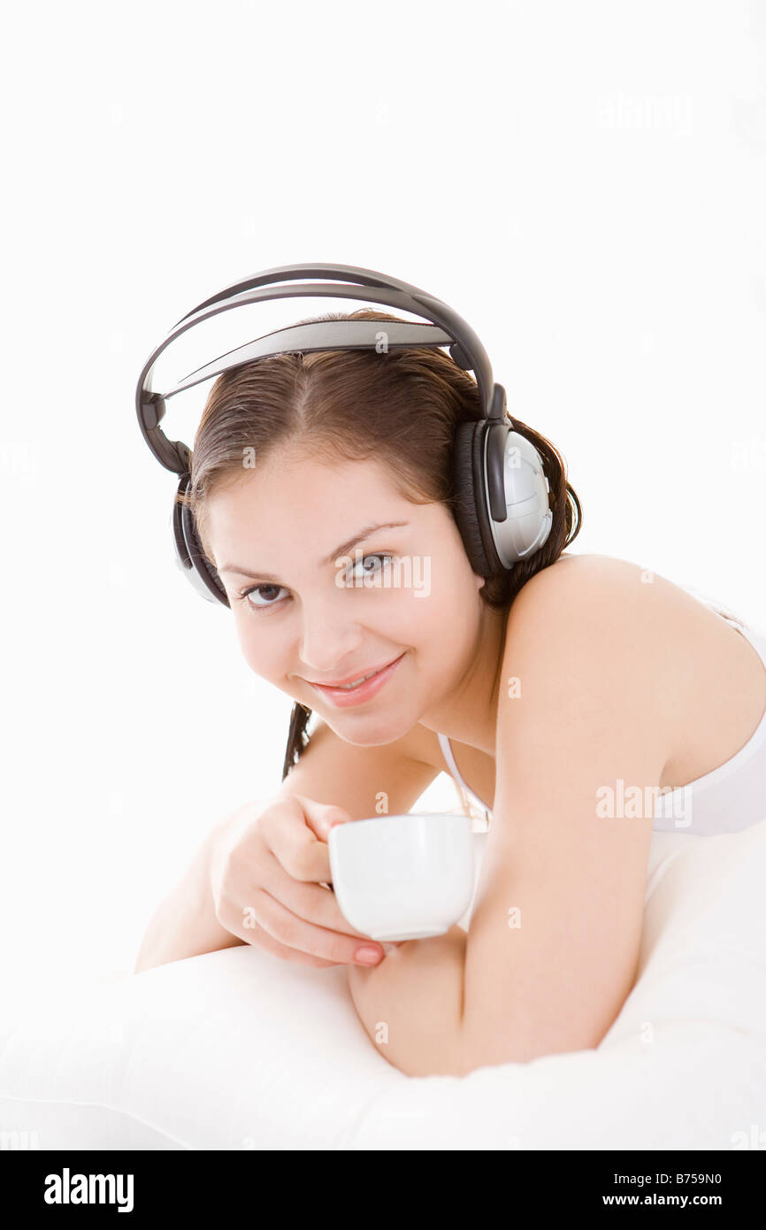 Teenage girl lying on bed wearing headphone holding cup Stock Photo - Alamy