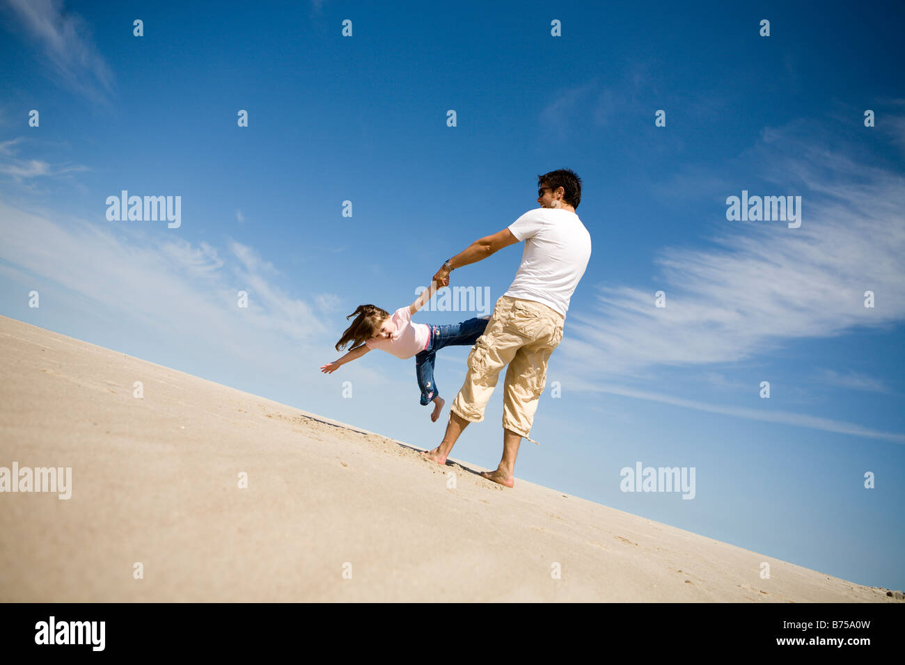Man swings girl (4) in circle, Grand Beach Provincial Park, Manitoba
