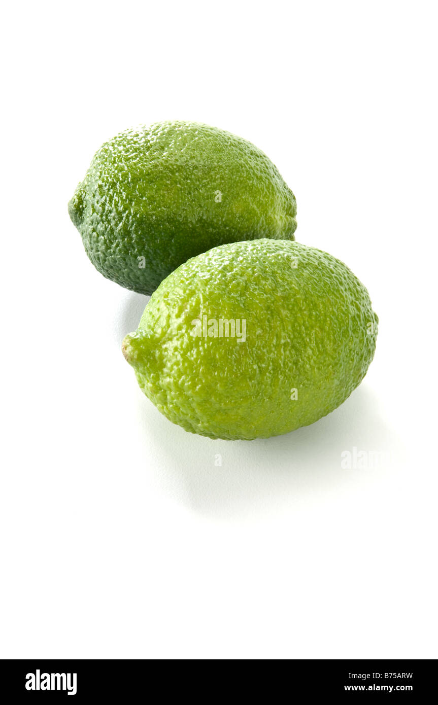 Close up of two limes placed on a white background. Each has a small shadow beneath. Stock Photo