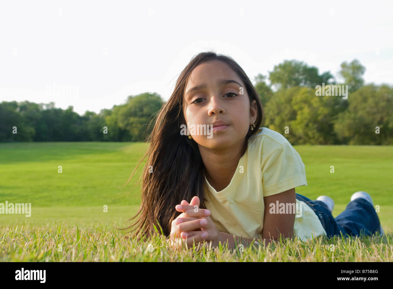 8 year old girl lying on grass in park, Winnipeg, Canada Stock Photo