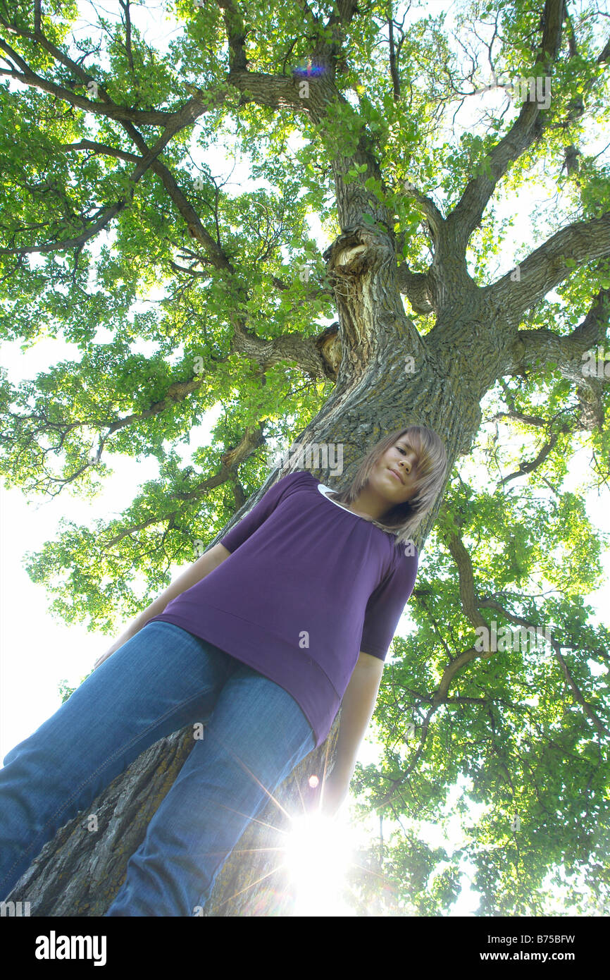 Low angle, 13 year old girl beside tree, Winnipeg, Canada Stock Photo