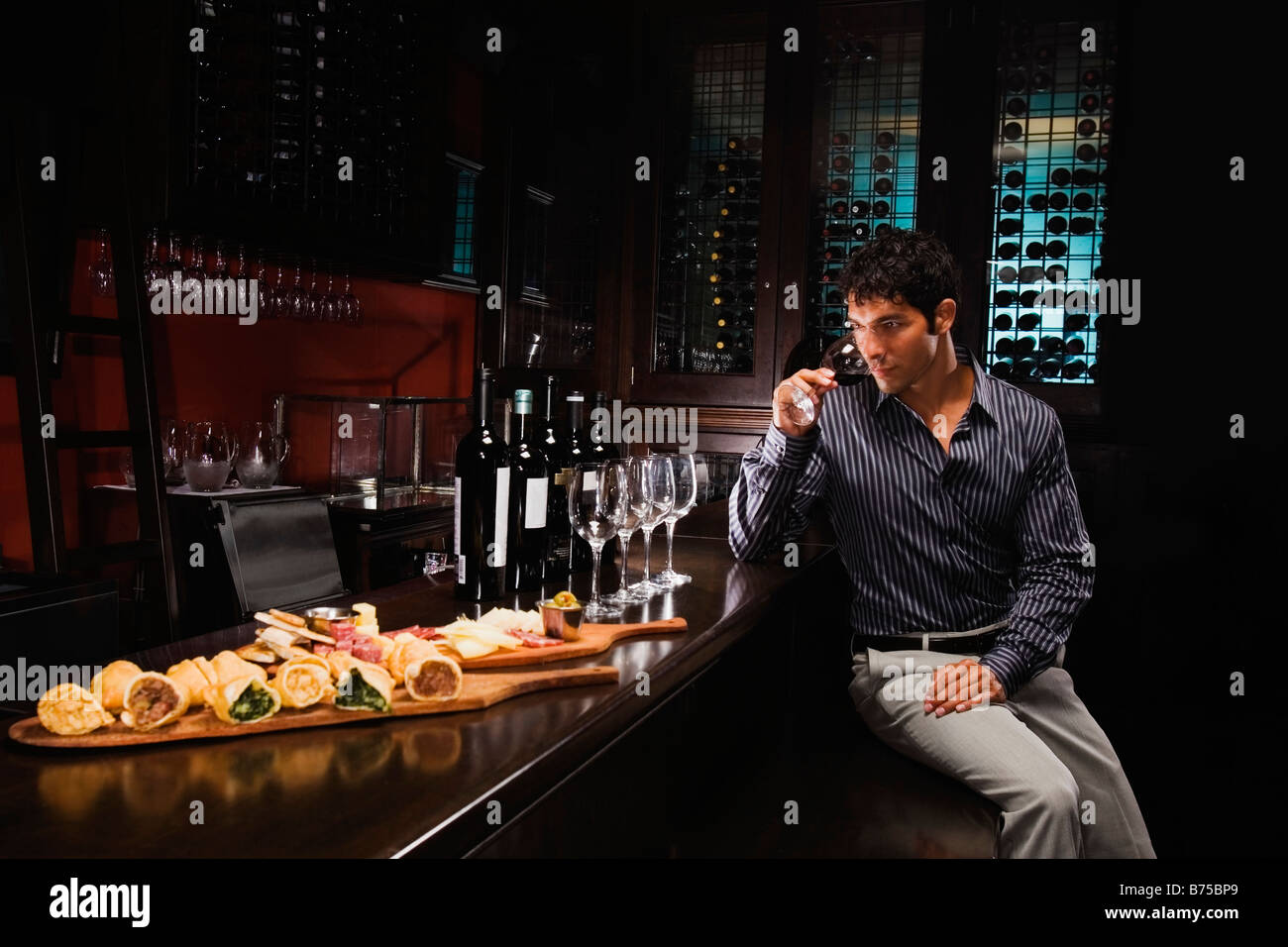 Young man sitting at a bar counter and drinking wine Stock Photo Alamy