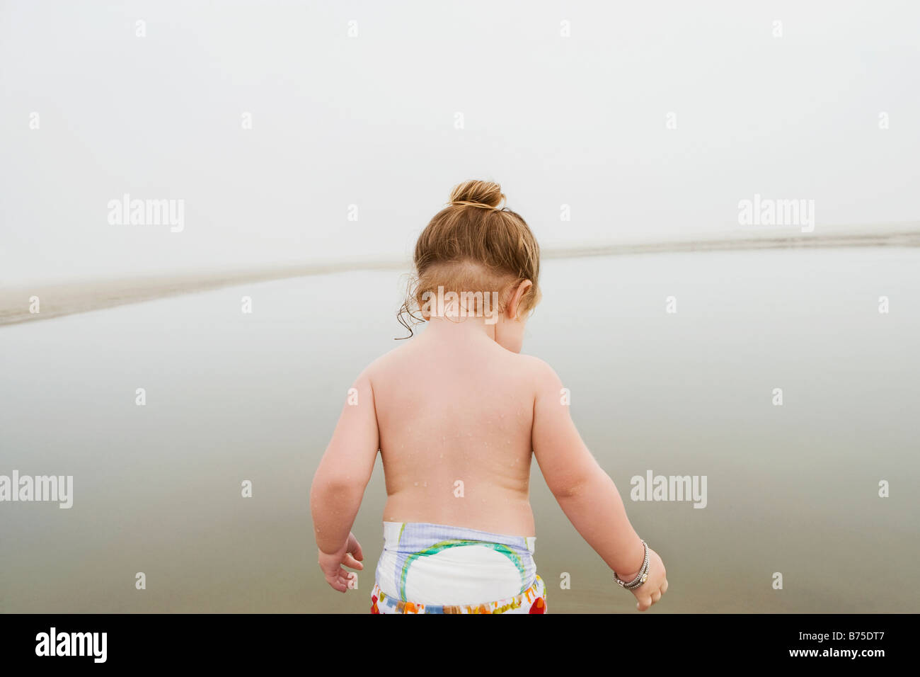 Rear view of a baby girl standing at the coast Stock Photo Alamy