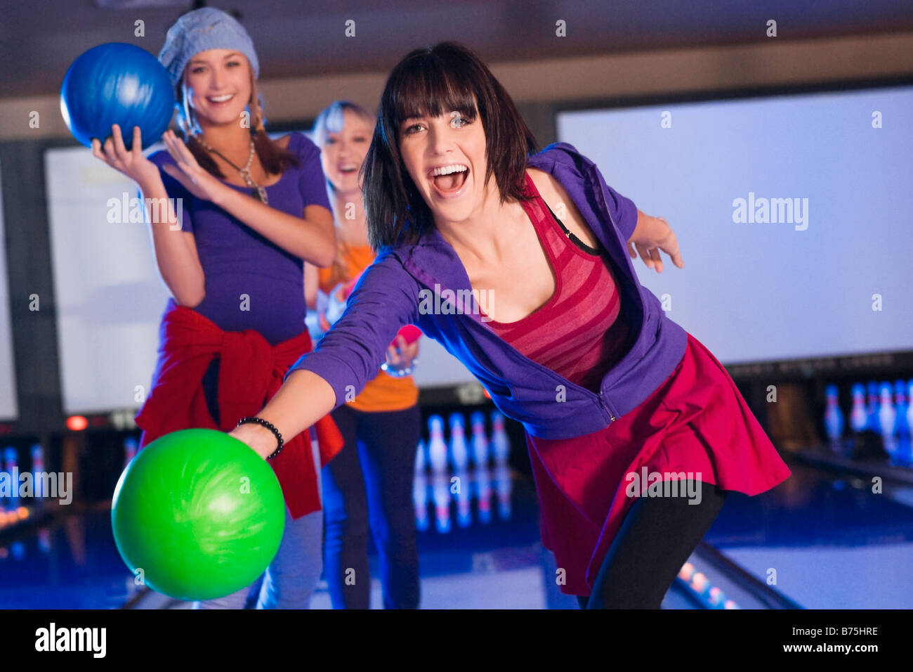 Portrait of a young woman throwing a ball with her friends in the background Stock Photo