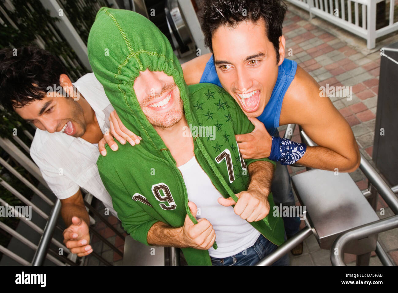 Three young men smiling together on a turnstyle Stock Photo - Alamy