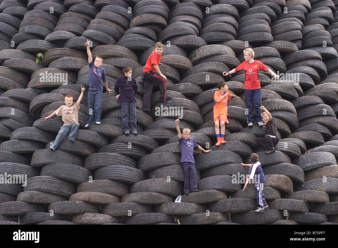 Boys playing on 12th July bonfire made almost entirely of tyres Lisburn Northern Ireland 2003. Stock Photo