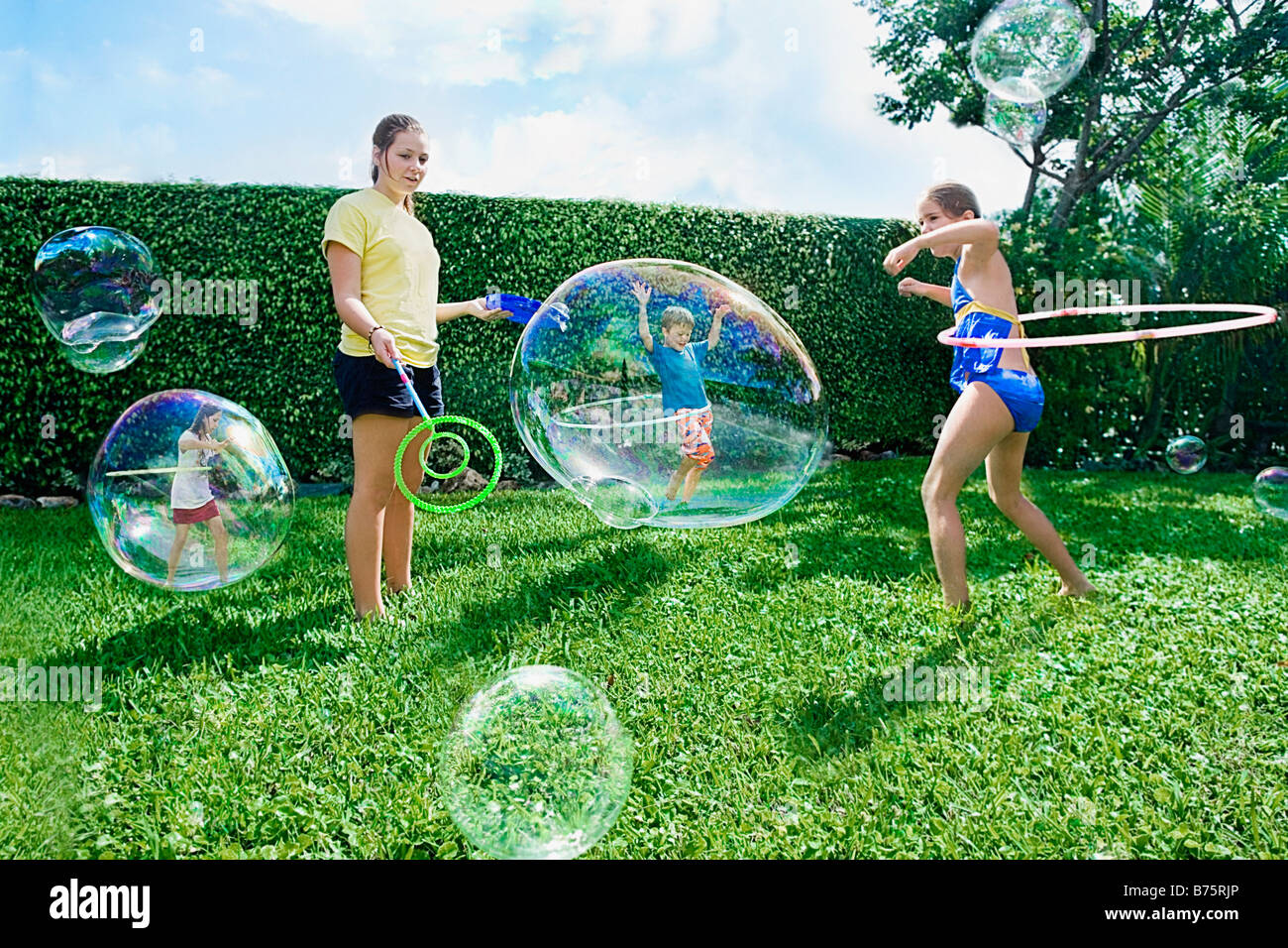 Four friends playing with bubbles and plastic hoop Stock Photo