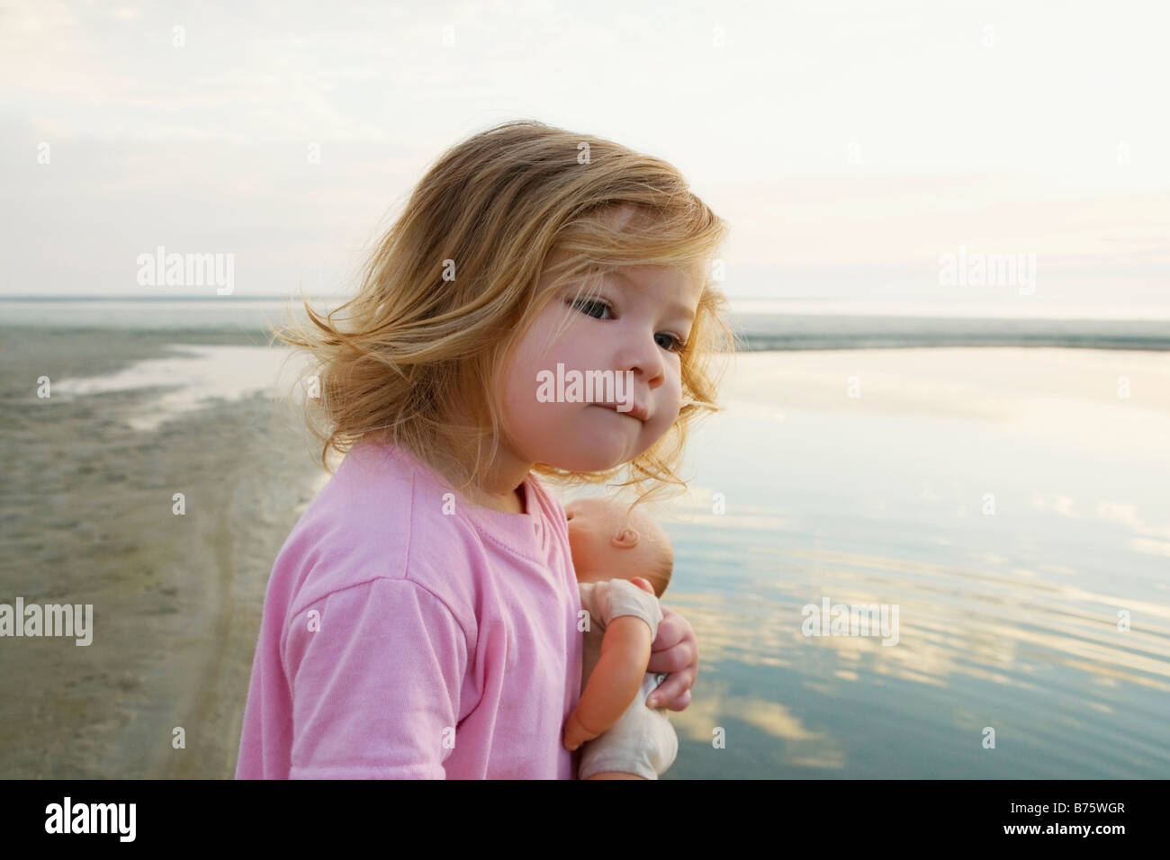 Side profile of a baby girl holding a doll and looking away Stock ...
