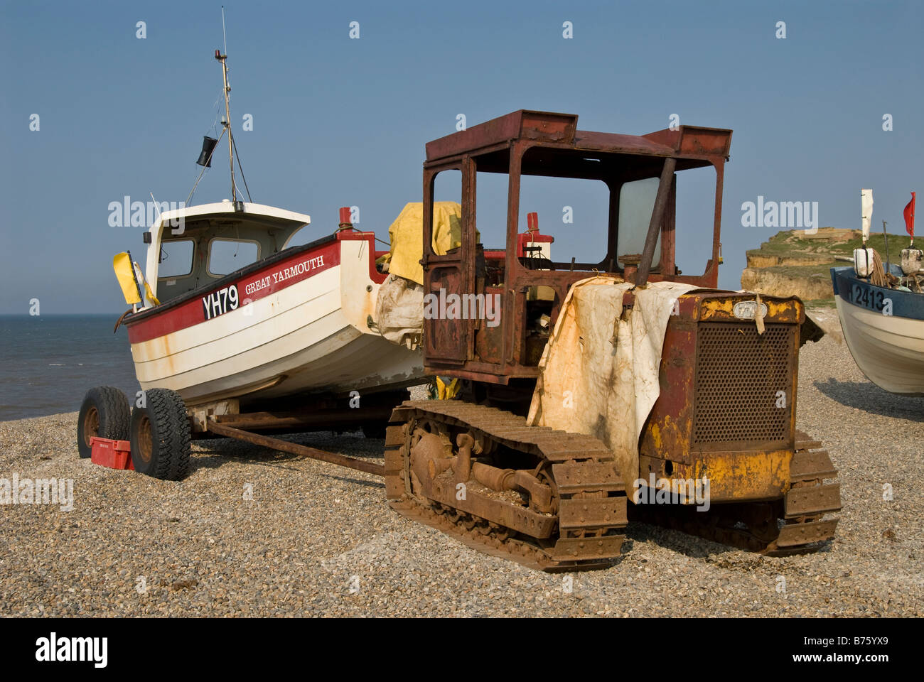 A rusty caterpillar tractor used to tow a fishing boat to and from the sea to the beach, Weybourne, Norfolk, Ungland, UK. Stock Photo