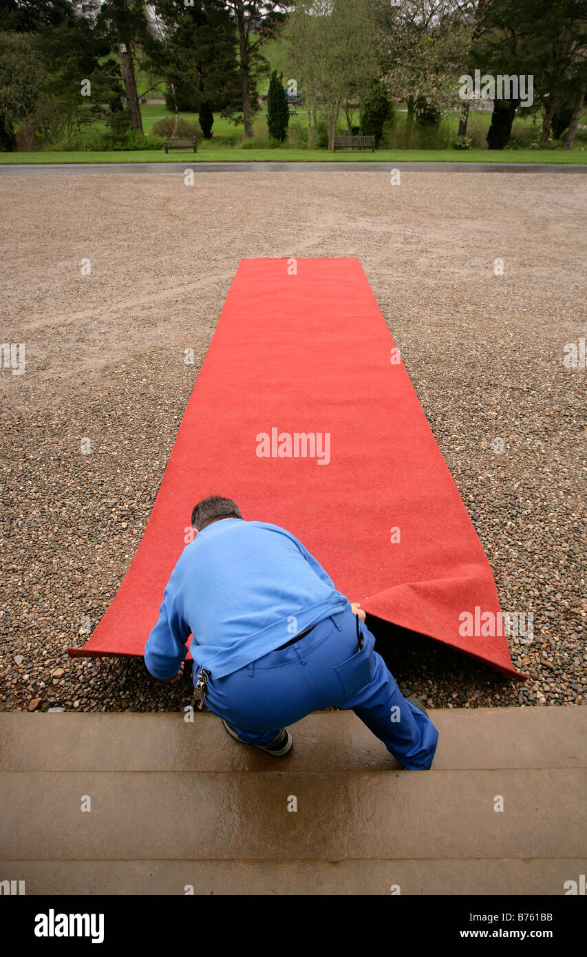 A man lays out a red carpet for a function at a Scottish castle Stock Photo