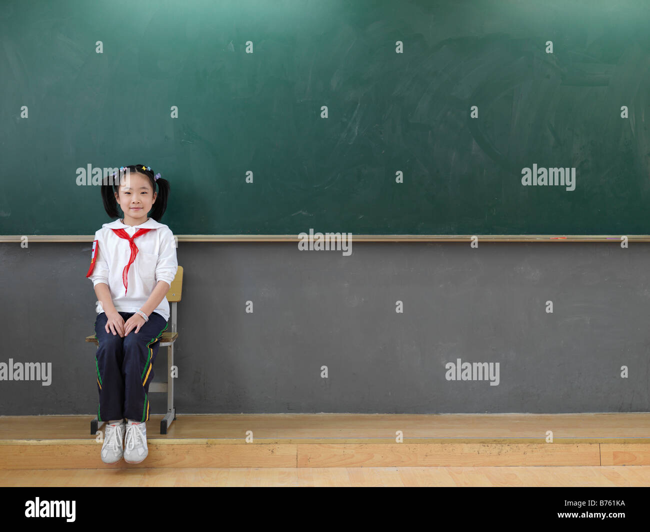 A portrait of a Chinese school girl sitting in front of a chalkboard