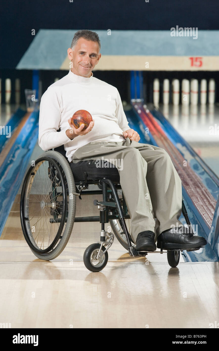 Portrait of a disabled mature man holding a bowling ball and smiling Stock Photo