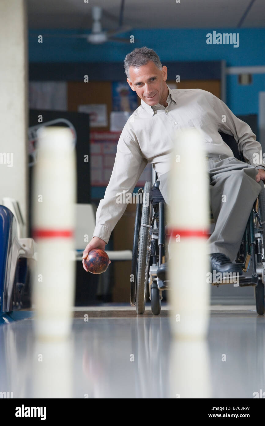 Disabled mature man playing ten pin bowling Stock Photo