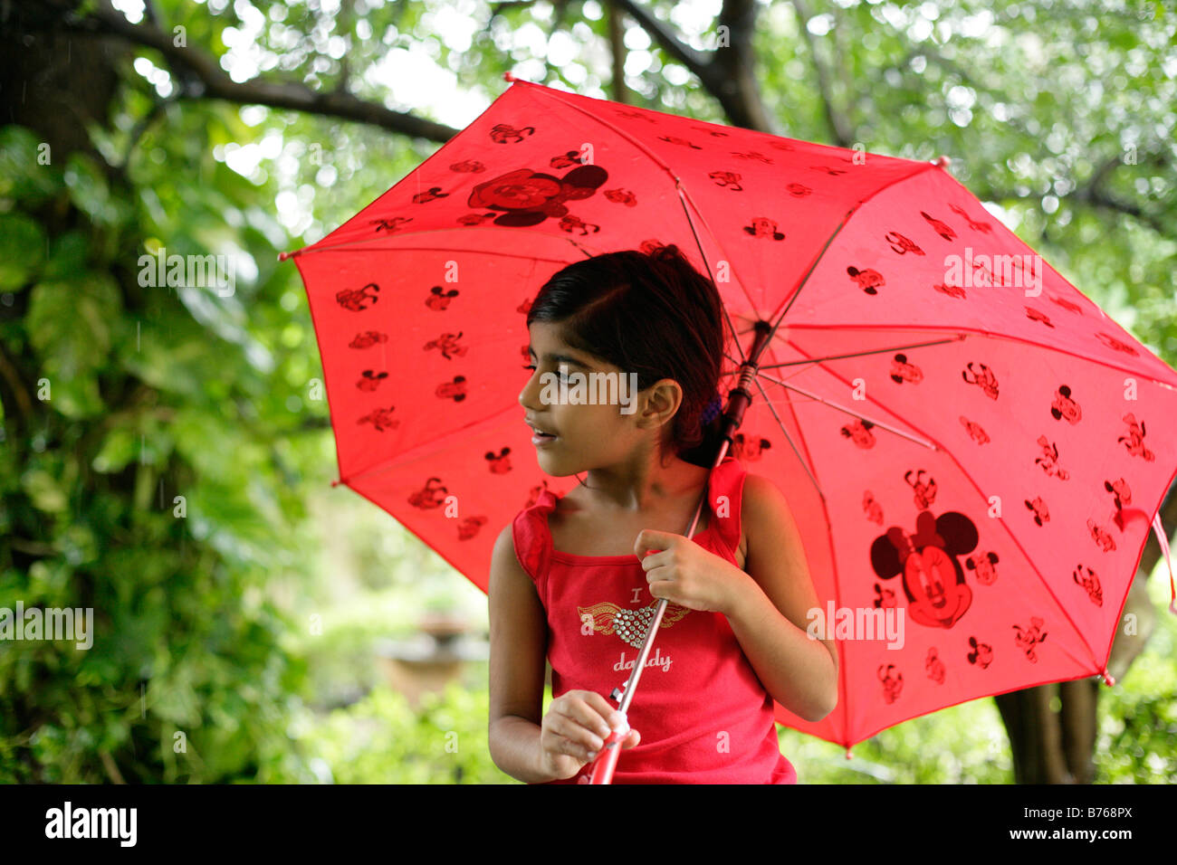 Innocent young girl holding an umbrella and enjoying the monsoon rains Stock Photo