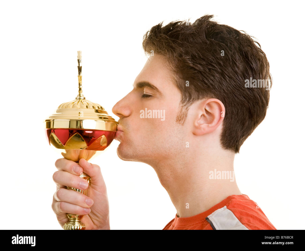 Junger Mann in Sportkleidung küsst einen Pokal Stock Photo