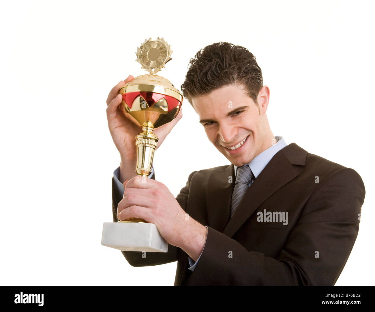 Junger Geschäftsmann im Anzug hält stolz einen Sportpokal Stock Photo