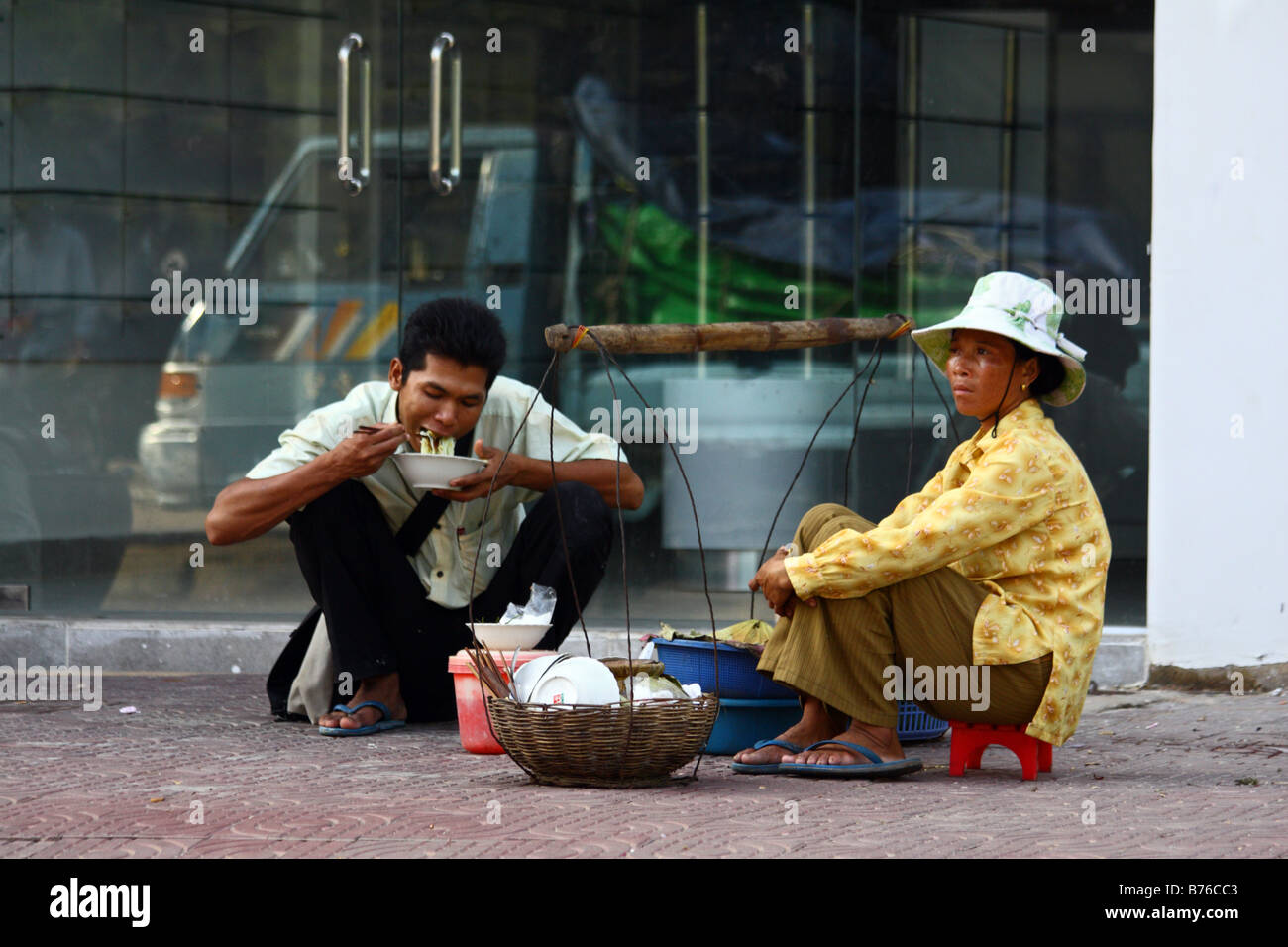Female street food vendor with one male customer eating on the street, Phnom Penn Cambodia South East Asia Stock Photo