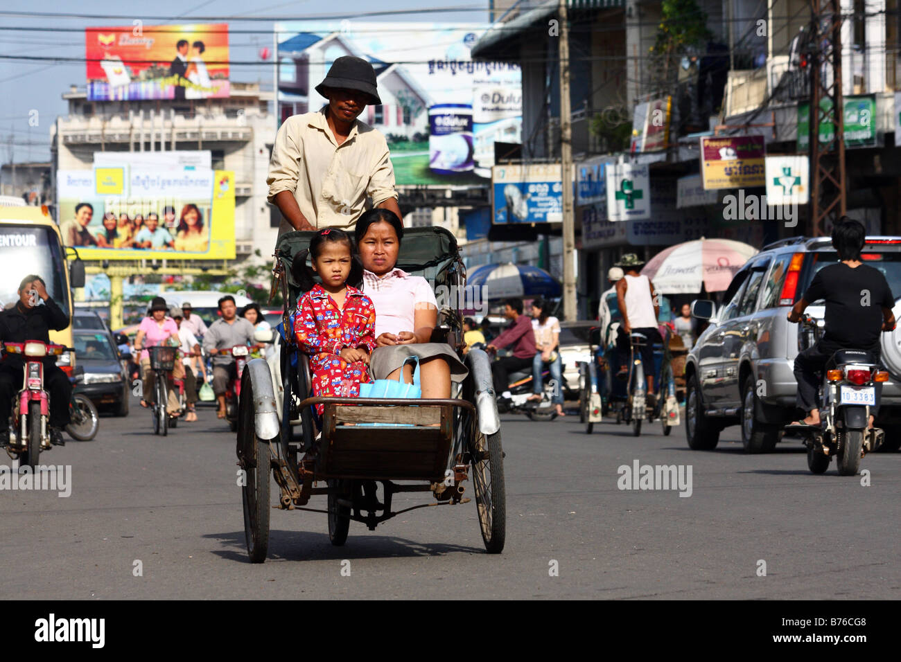 Cyclo driver with two customer in the streets in Phnom Penh, Cambodia Stock Photo