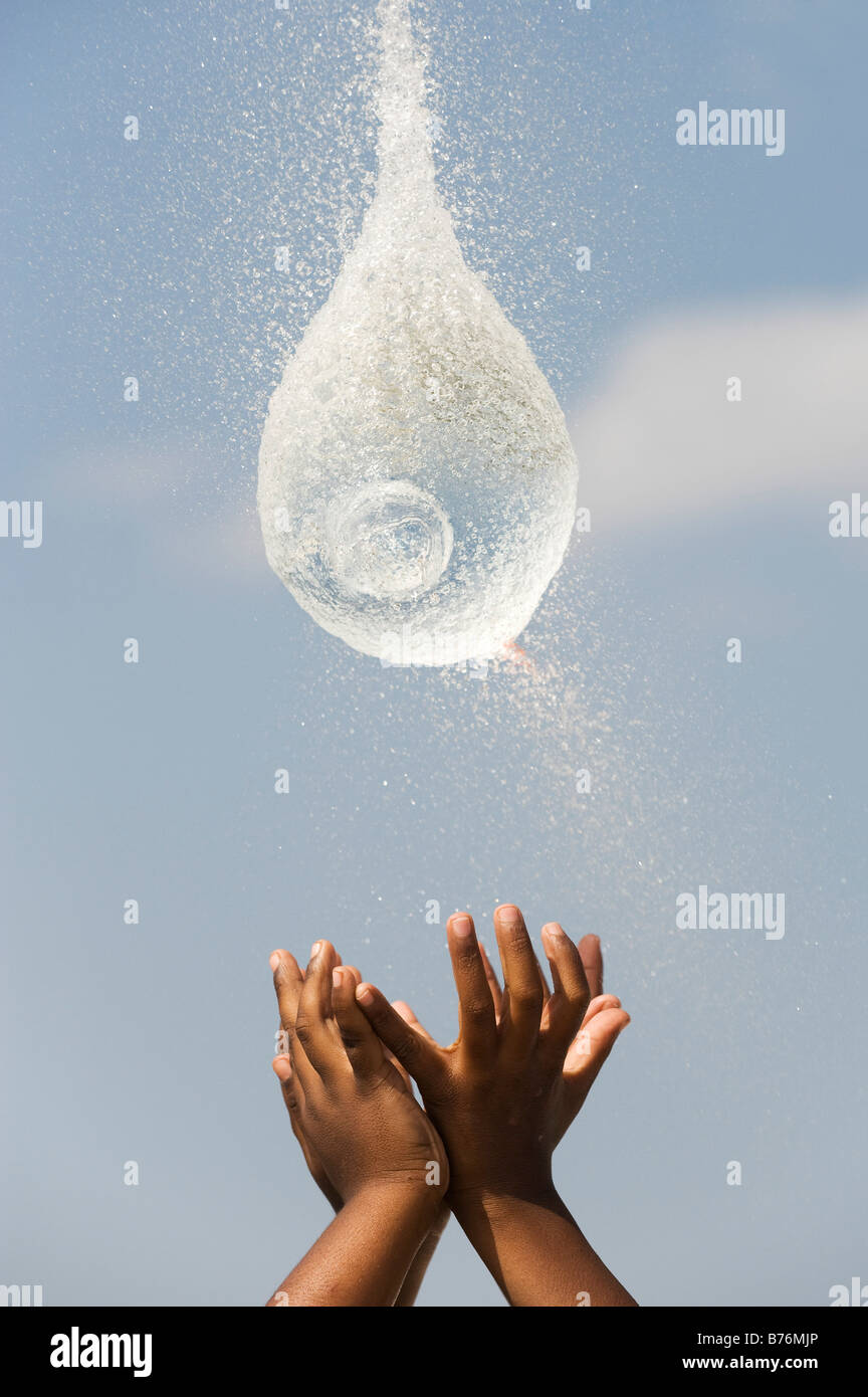Indian boys catching a burst water balloon. India Stock Photo