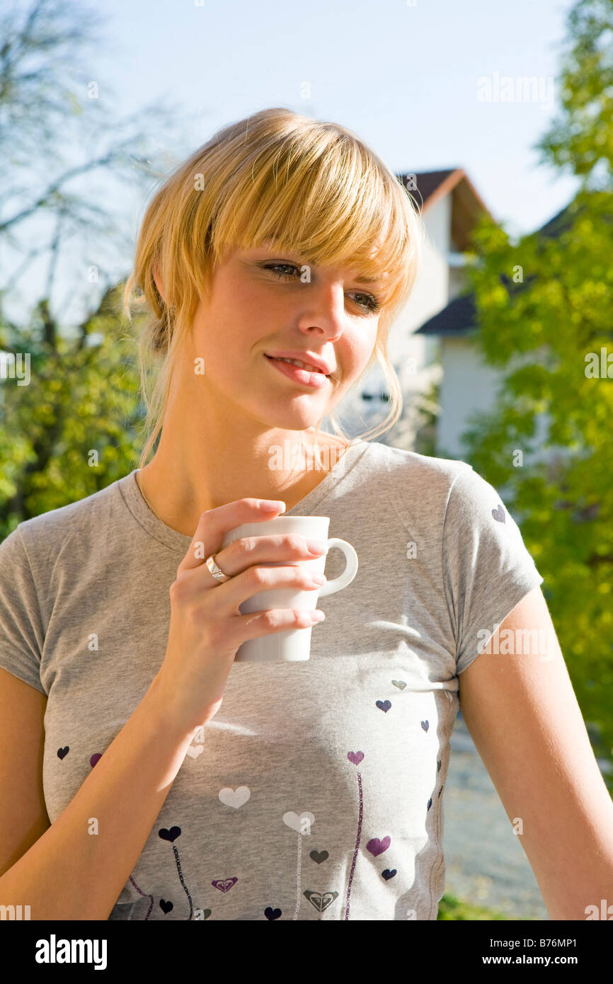 Frau mit Kaffetasse an der Balkontuer, Woman standing in doorway with coffee mug Stock Photo