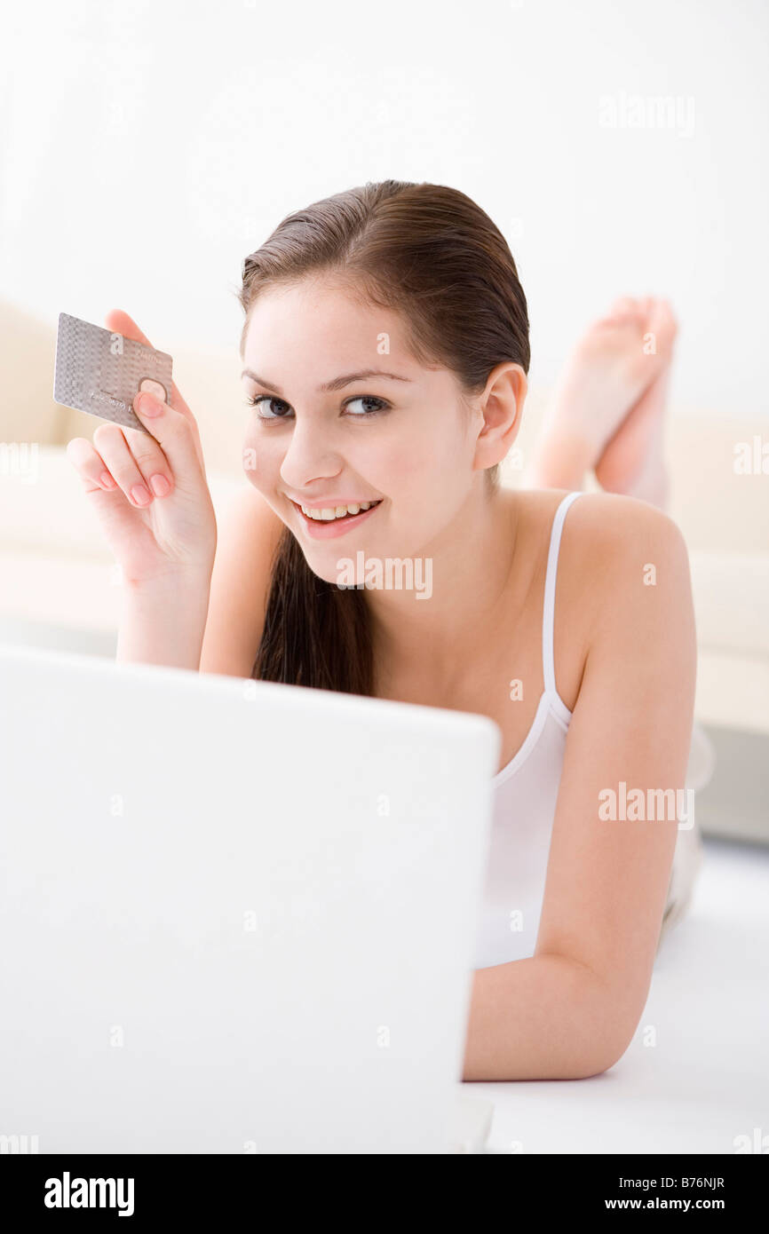 Teenage girl 13 15 lying on floor using laptop holding credit card Stock Photo