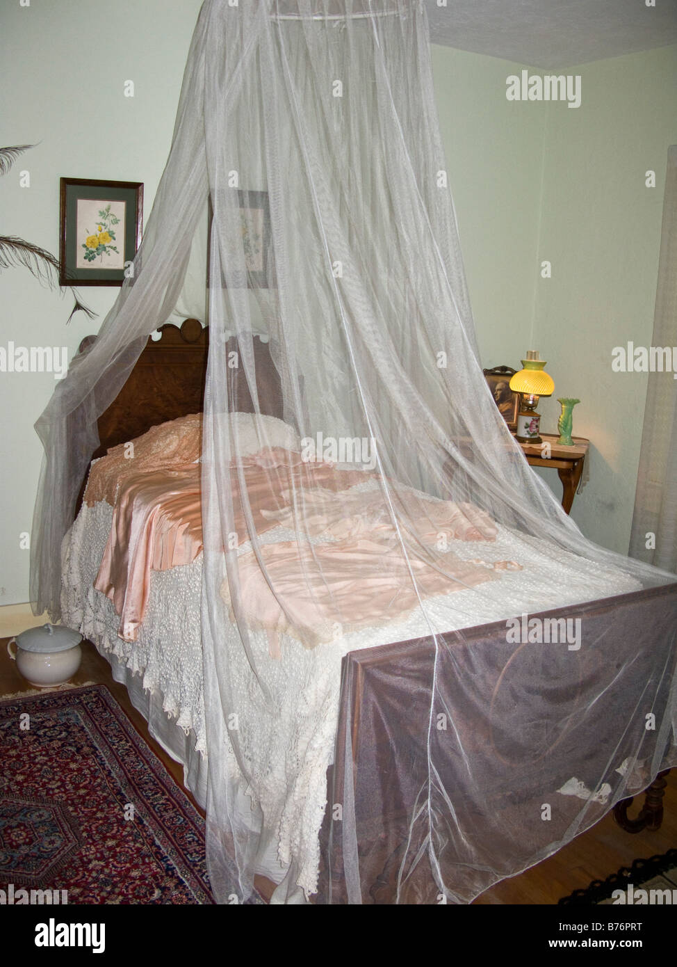 Mosquito netting around bed in 1930's style American plantation house bedroom Stock Photo