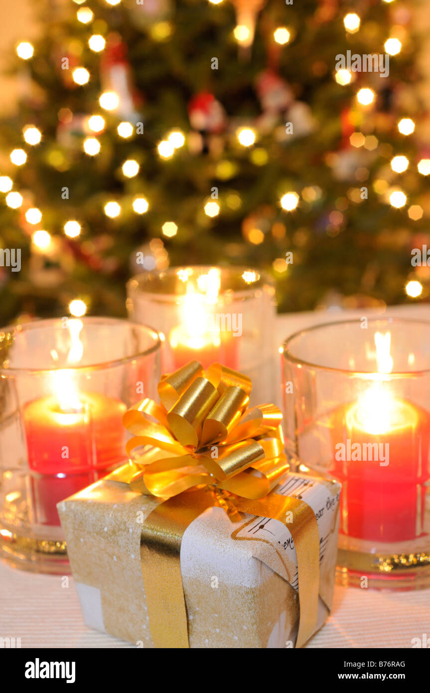 Wrapped Christmas present with candles and lighted tree in background