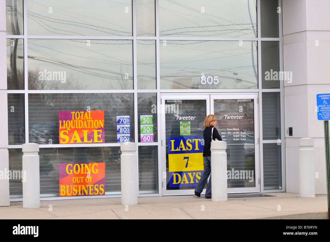 Storefront of a retail store going out of business signs with woman at