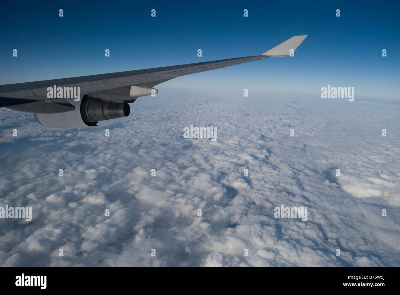 View of clouds and aircraft wing through window of Air Philippines Boeing 747 Jumbo jet Stock Photo