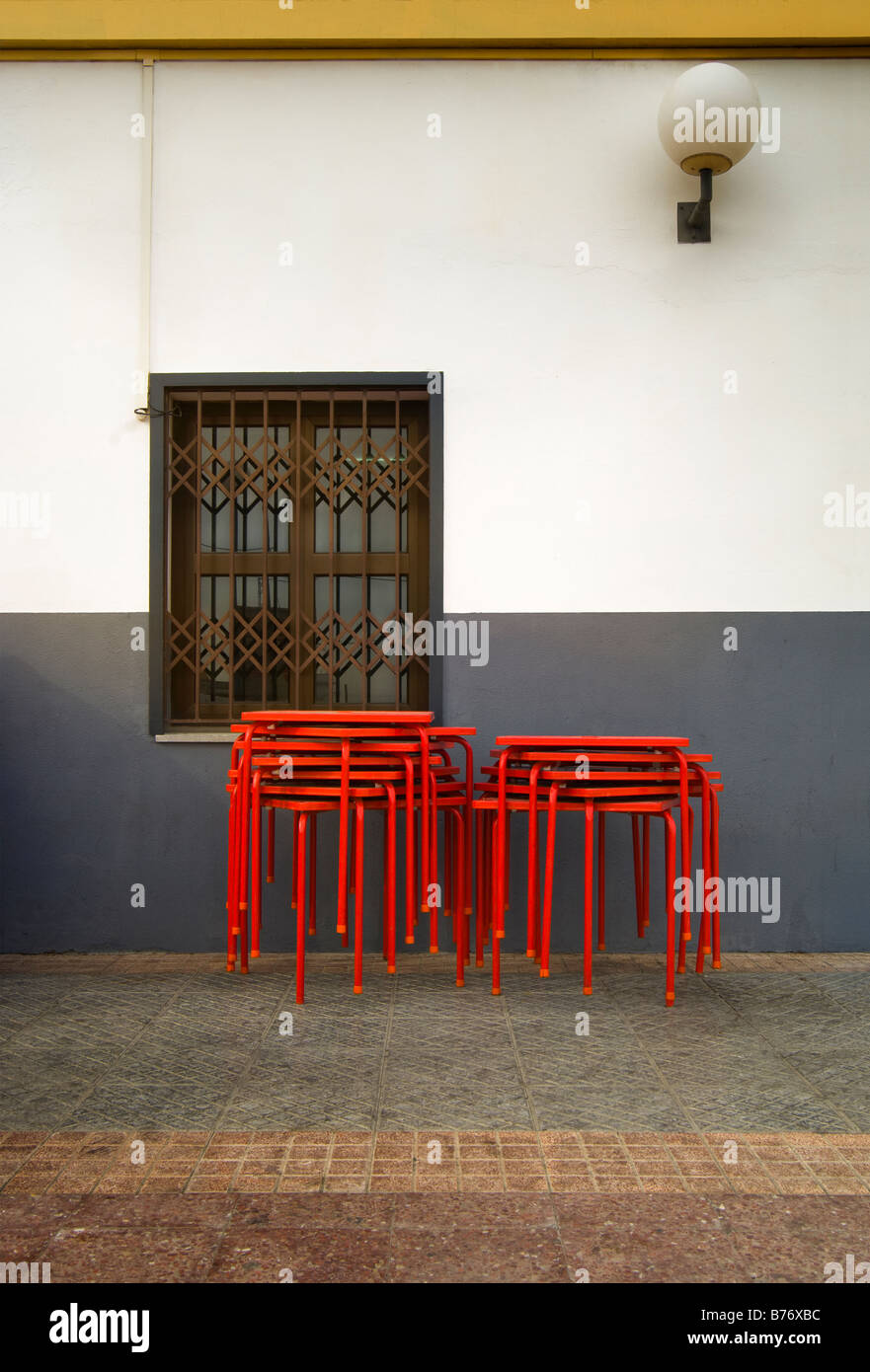 Cafe at railway station in Chiclana de la Frontera Andalusia Spain showing stack of red tables outside shuttered window Stock Photo