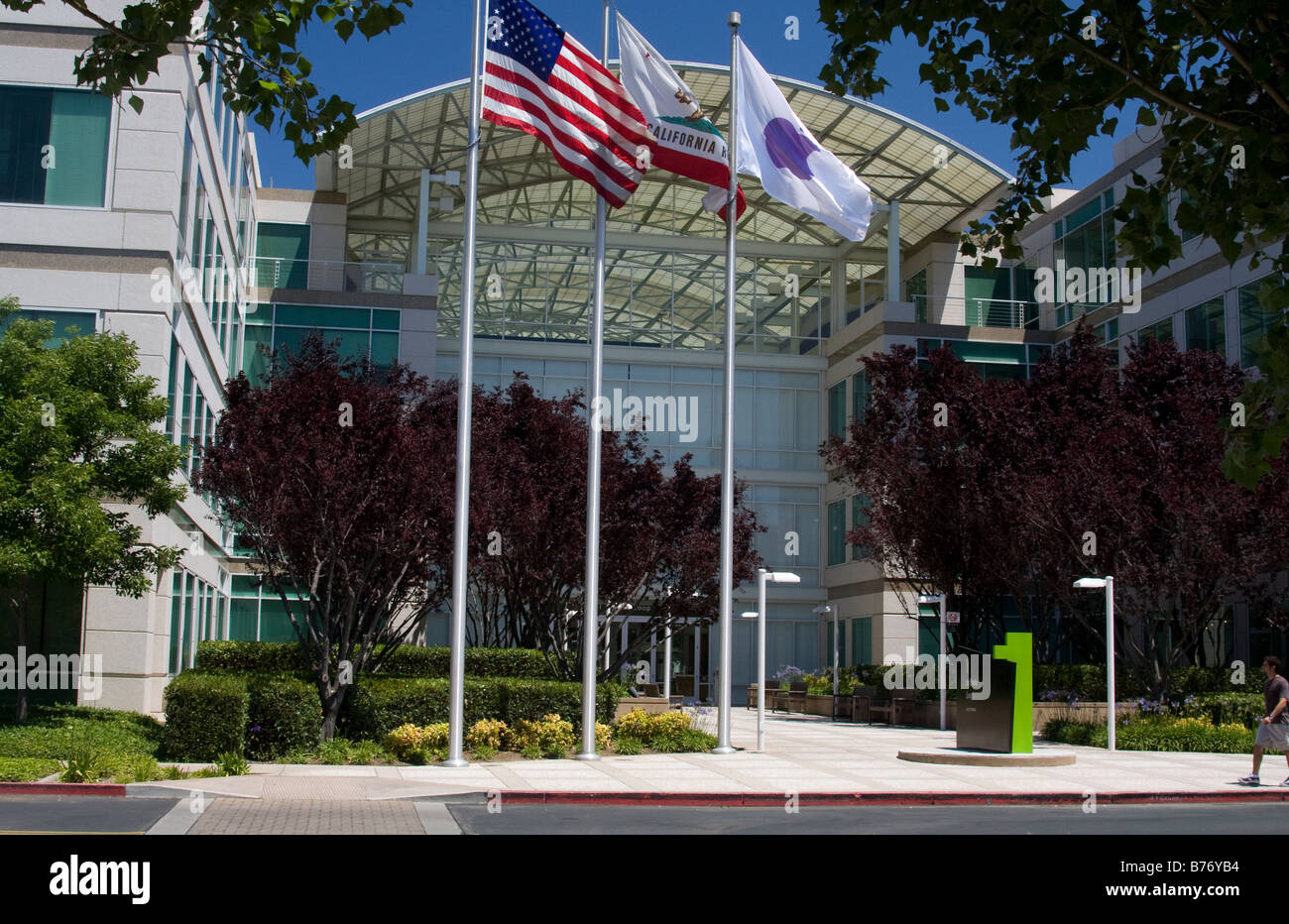 Front entrance of Apple, Inc. headquarters (AAPL) with flagpoles showing Apple flag with US and California flags. Stock Photo