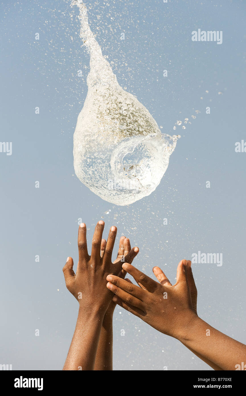 Indian boys catching a burst water balloon. India Stock Photo