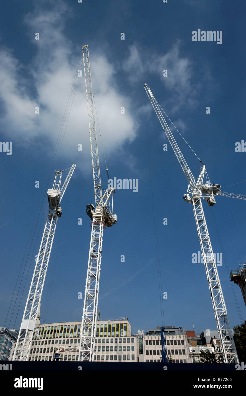 Three white cranes against a blue sky Stock Photo