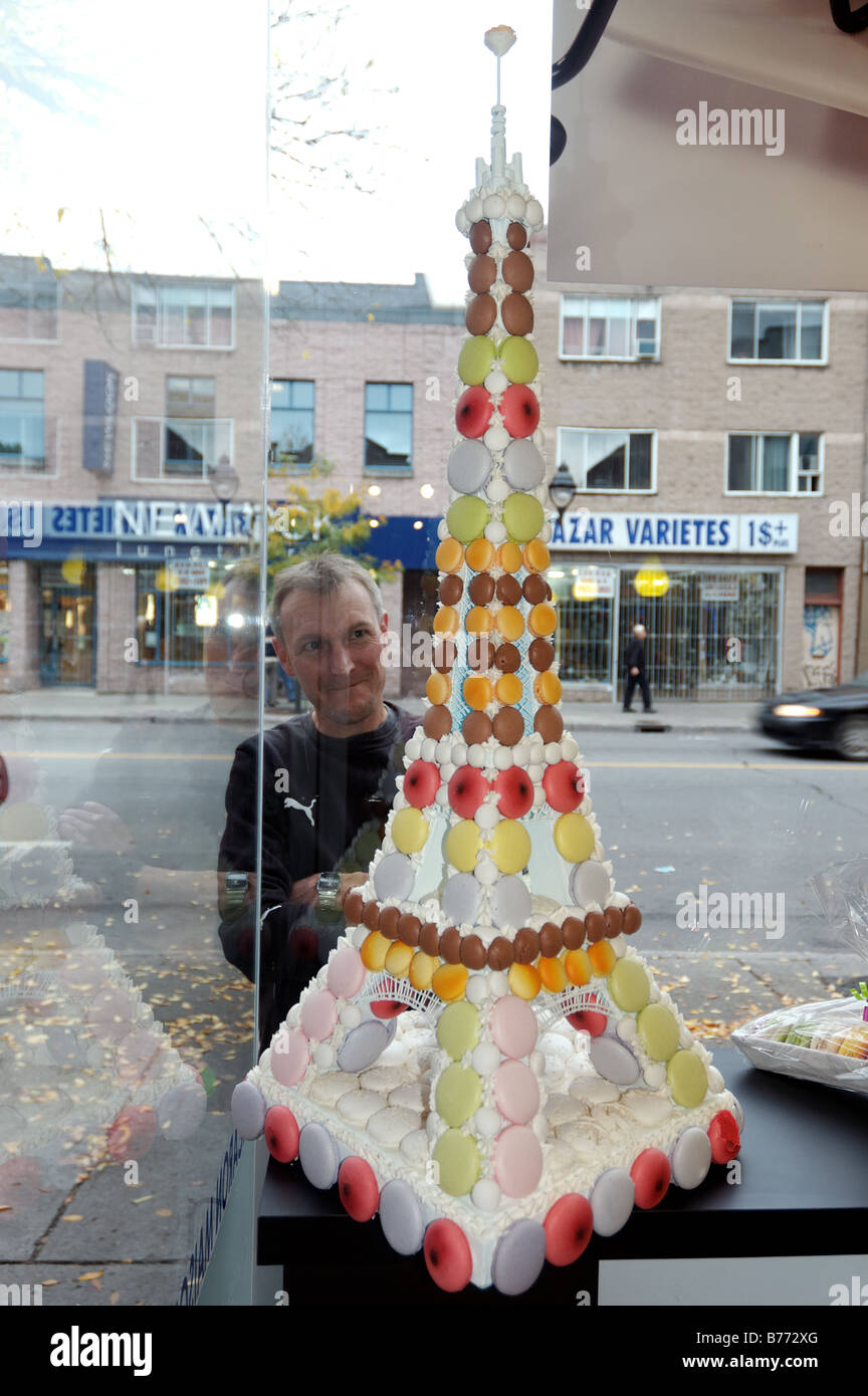 A man looking through a shop window at an Eiffel Tower made from sweets Stock Photo