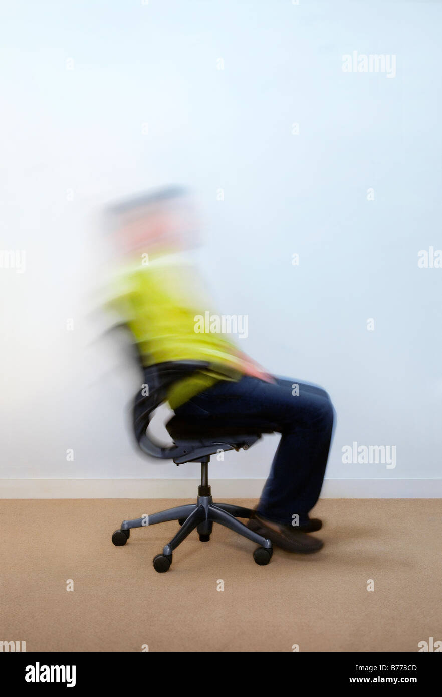 Man rocking back and forth on office chair Stock Photo